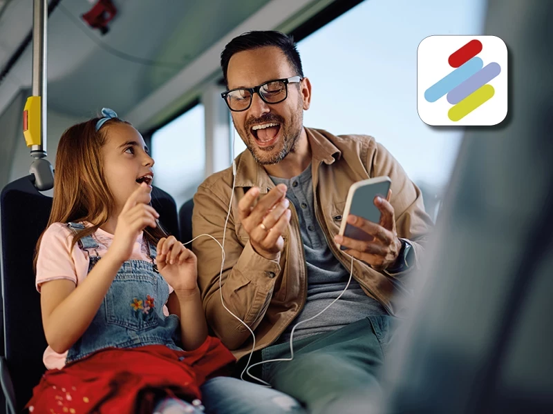 Vater und Tochter sitzen im Bus und hören Musik auf dem Smartphone