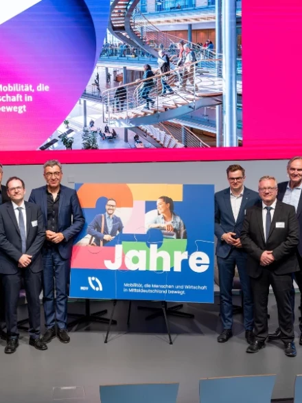 Ein Puzzle zwischen elf Personen auf einer Bühne