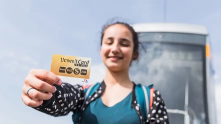 Junge Frau hält UmweltCardGOLD in die Kamera