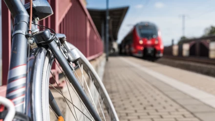 Ein Fahrrad steht am Bahnhof Grimma, im Hintergrund fährt ein Zug ein