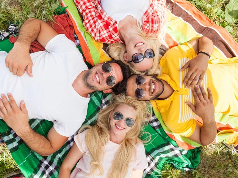 4 junge Leute liegen gemeinsam auf einer Wiese