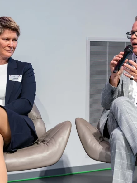 Mann und Frau sitzen im Sessel bei einer Podiumsdiskussion