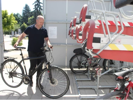 Ein Mann schiebt ein Fahrrad in eine Radabstellanlage