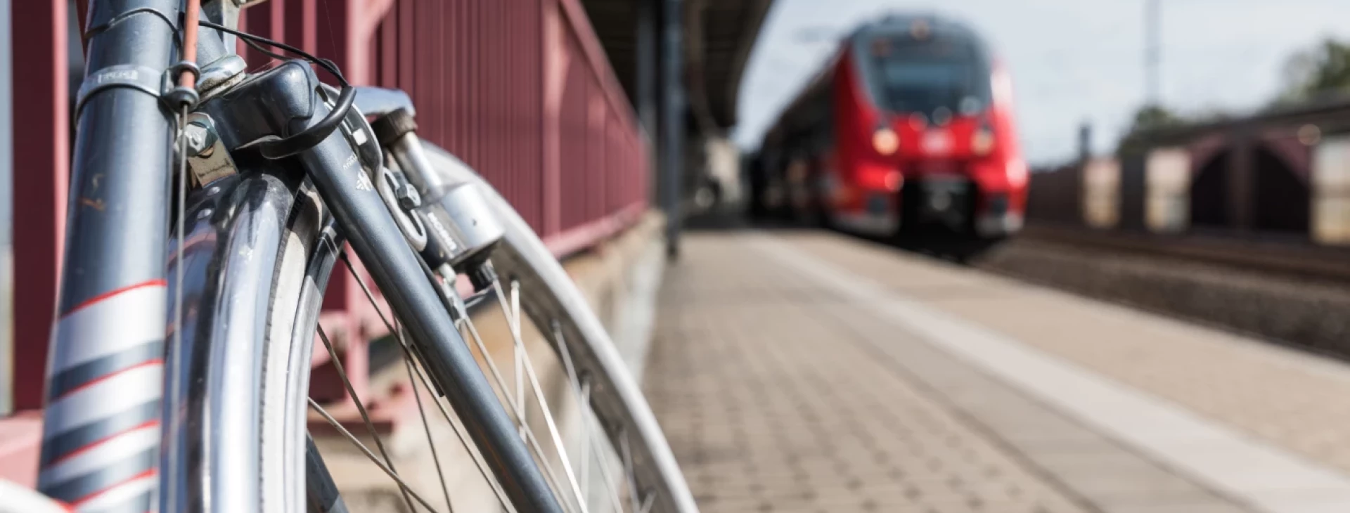 Ein Fahrrad steht am Bahnhof Grimma, im Hintergrund fährt ein Zug ein