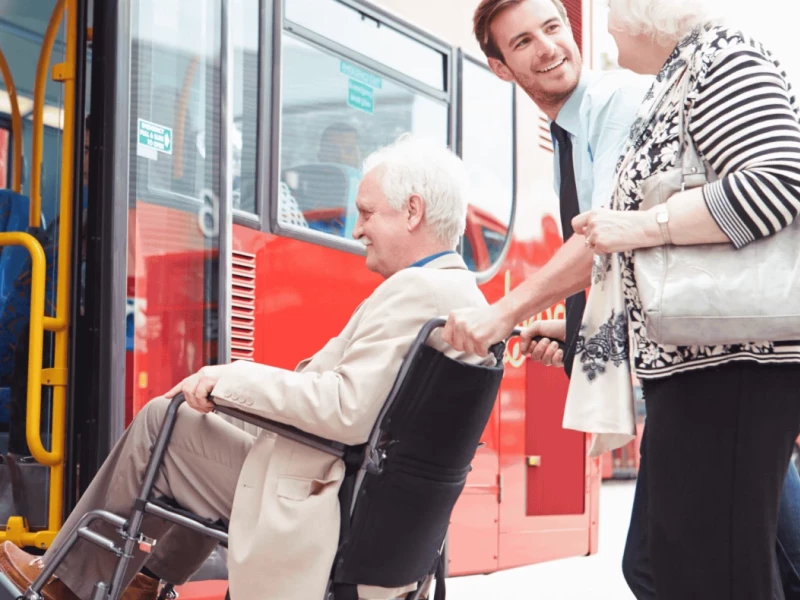 Ältere Person im Rollstuhl wird in die Bahn geschoben