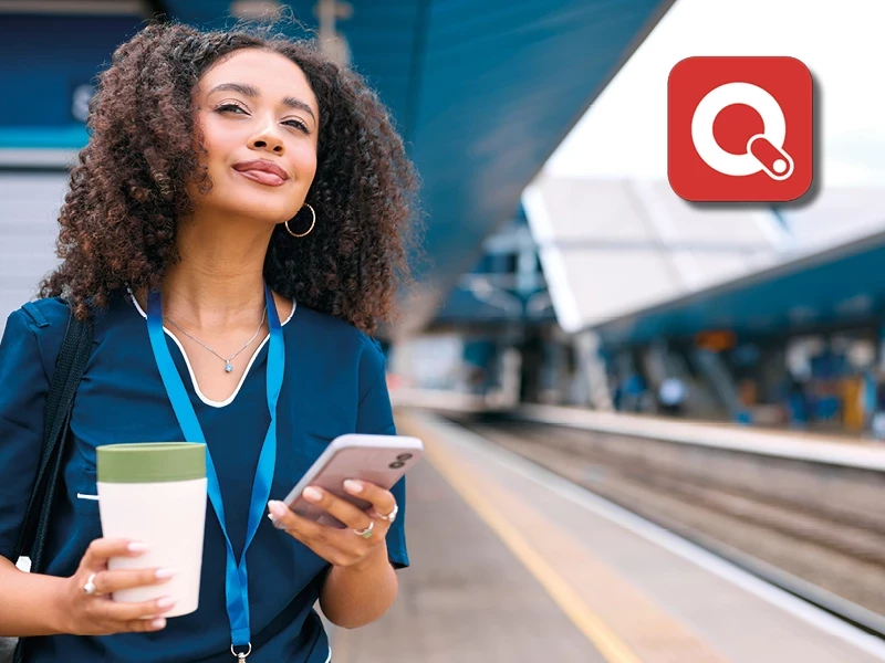 Frau mit ihrem Smartphone auf einem Bahnsteig