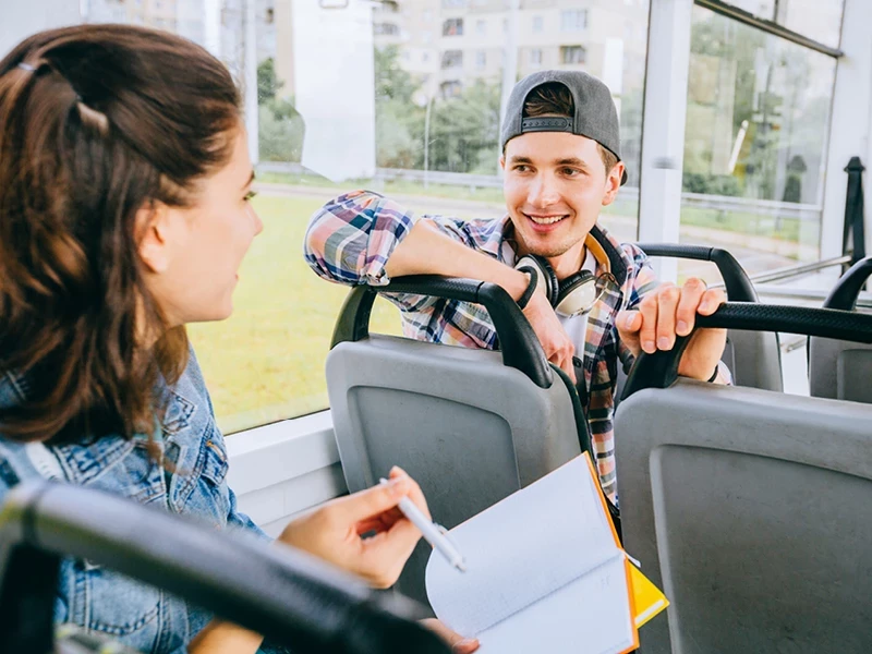 Ein junger Mann im Bus spricht mit einer jungen Frau hinter ihm