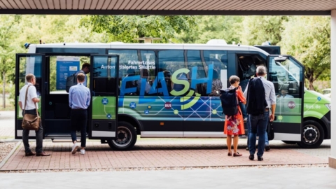 FLASH-Bus steht zur Abfahrt bereit mit geöffneten Türen, mehrere Teilnehmende der Veranstaltung steigen ein
