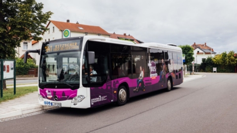 PlusBus an einer Haltestelle mit Häusern im Hintergrund PlusBus an einer Haltestelle mit Häusern im Hintergrund