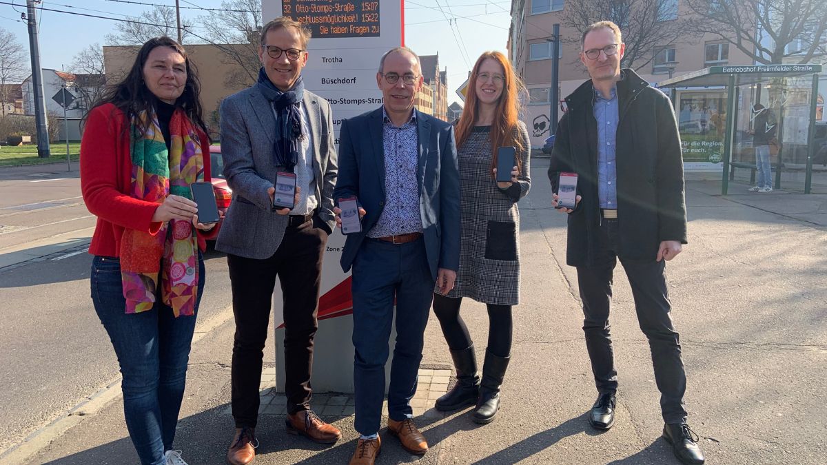 Iris Rudolph (Pressesprecherin SWH/HAVAG), Steffen Lehmann (MDV-Geschäftsführer), Andreas Völker (Marketing- und Vertriebsleiter HAVAG), Emma Backer (Projektsteuerin SL+ beim MDV), René Brandenburg (Abteilungsleiter Prozesse) an einer Haltestelle in Halle mit Smartphone in der Hand Iris Rudolph (Pressesprecherin SWH/HAVAG), Steffen Lehmann (MDV-Geschäftsführer), Andreas Völker (Marketing- und Vertriebsleiter HAVAG), Emma Backer (Projektsteuerin SL+ beim MDV), René Brandenburg (Abteilungsleiter Prozesse) an einer Haltestelle in Halle mit Smartphone in der Hand